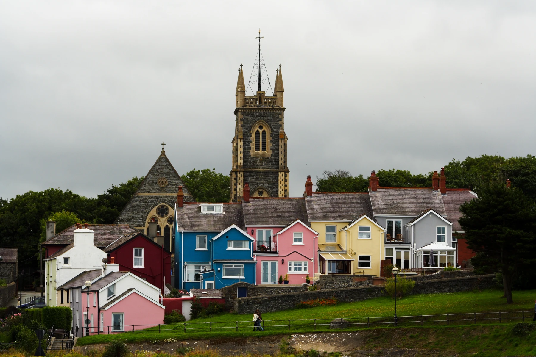 Pink, yellow and blue houses beneath the church tower in Aberaeron, Wales.